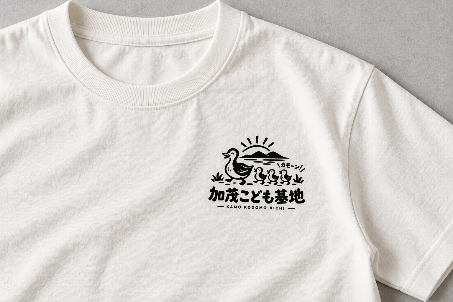 コットンTシャツの左胸に小さく印刷した加茂こども基地のロゴのアップ